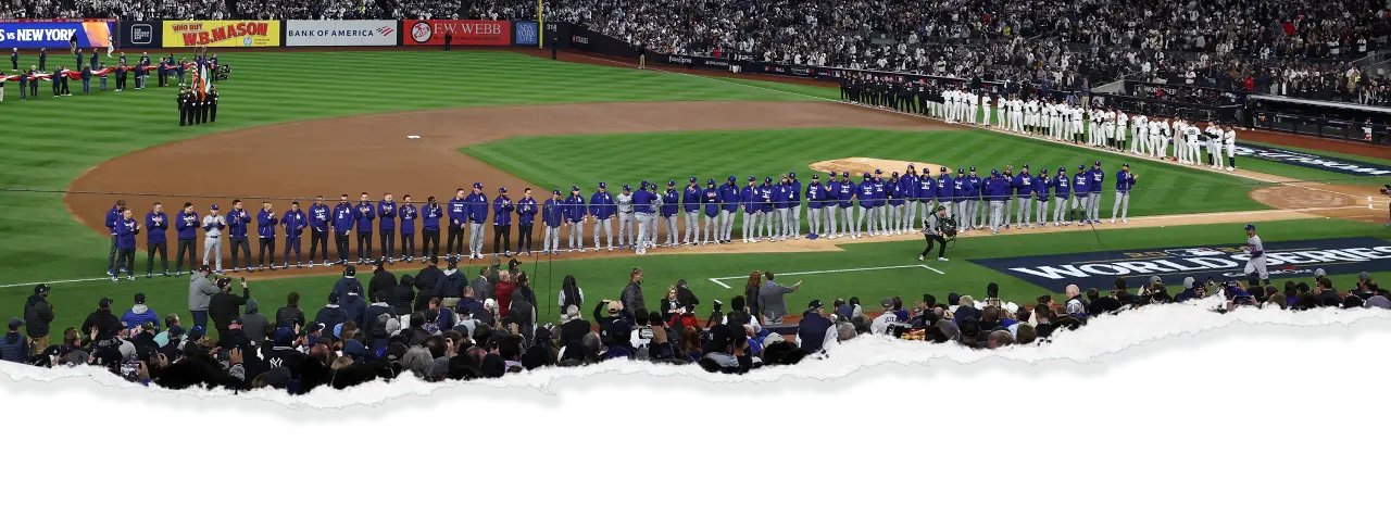 Both the New York Yankees and Los Angeles Dodgers teams lined up along the baseball diamond for the national anthem, with fans in the stadium watching on during a World Series game. A torn paper effect is added at the bottom, enhancing the dramatic presentation of the scene.