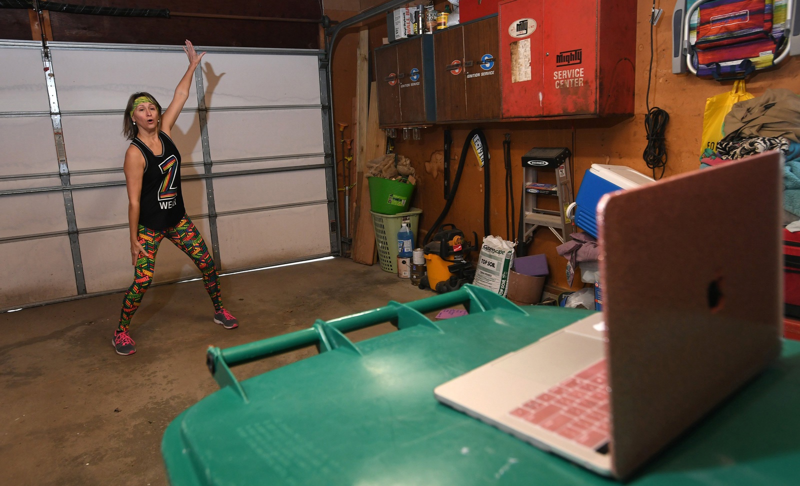 A woman streams a fitness class in her garage.