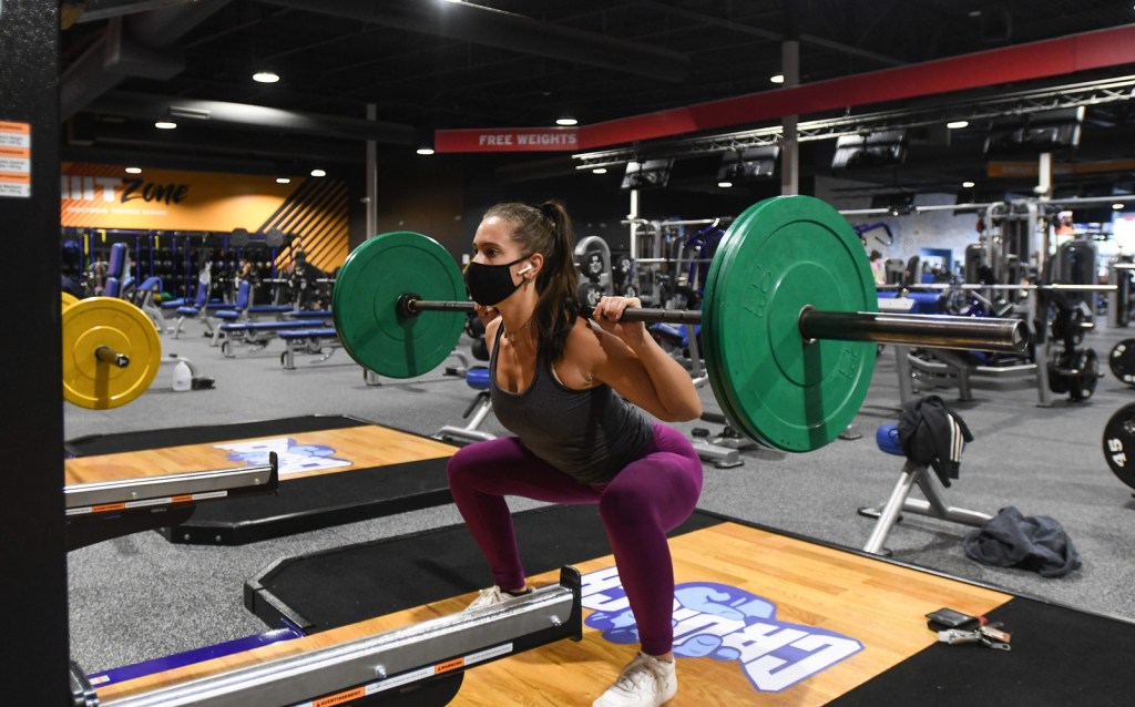 A woman squats at a gym