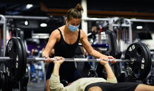 A woman spots someone while they bench press.