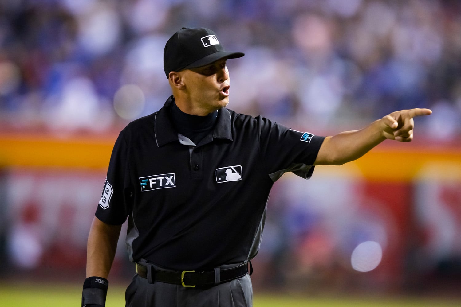 MLB umpire with FTX logo advertisement on his shirt points towards the dug out