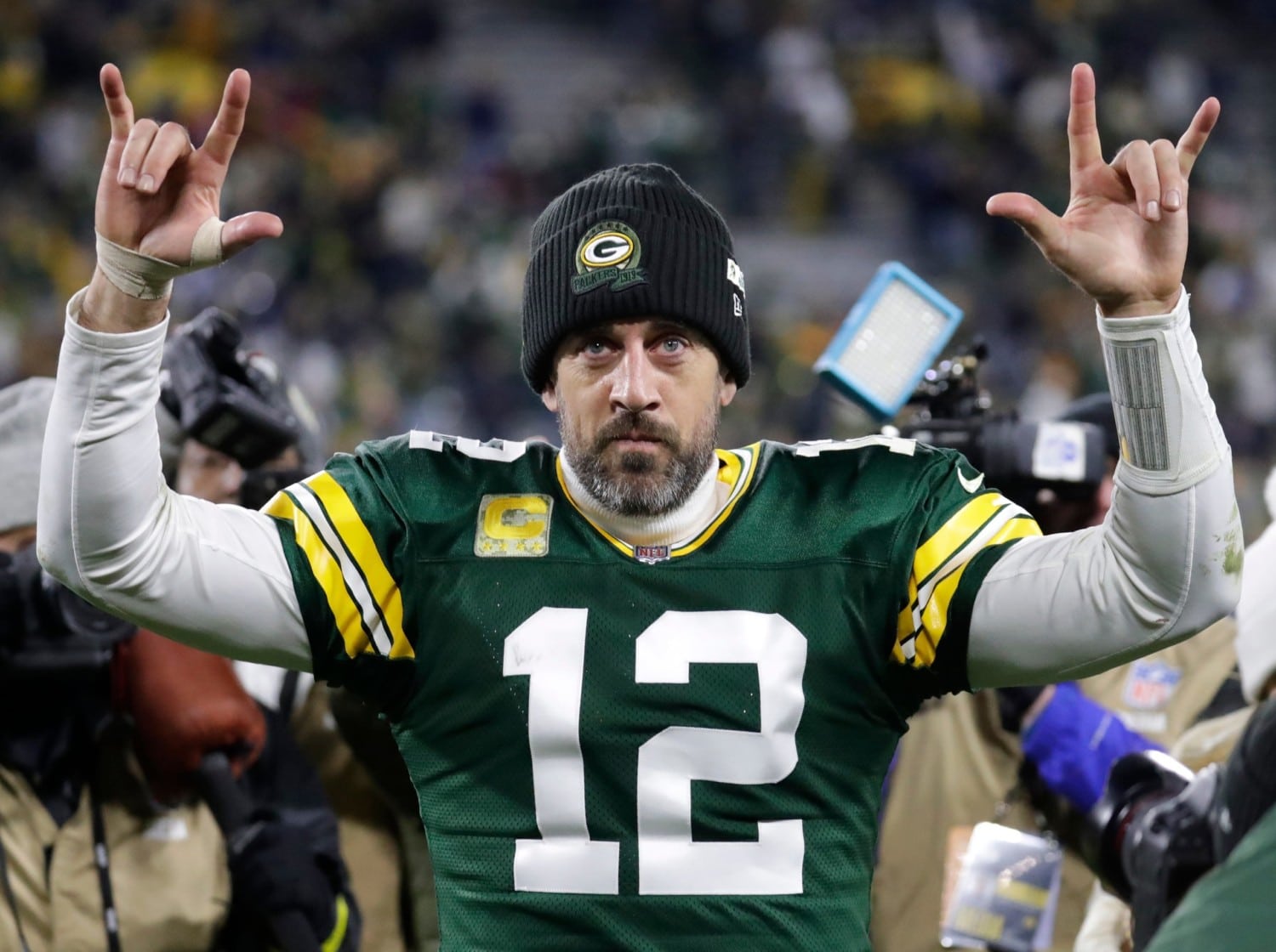 Green Bay Packers quarterback Aaron Rodgers walks off field while being surrounded by photographers