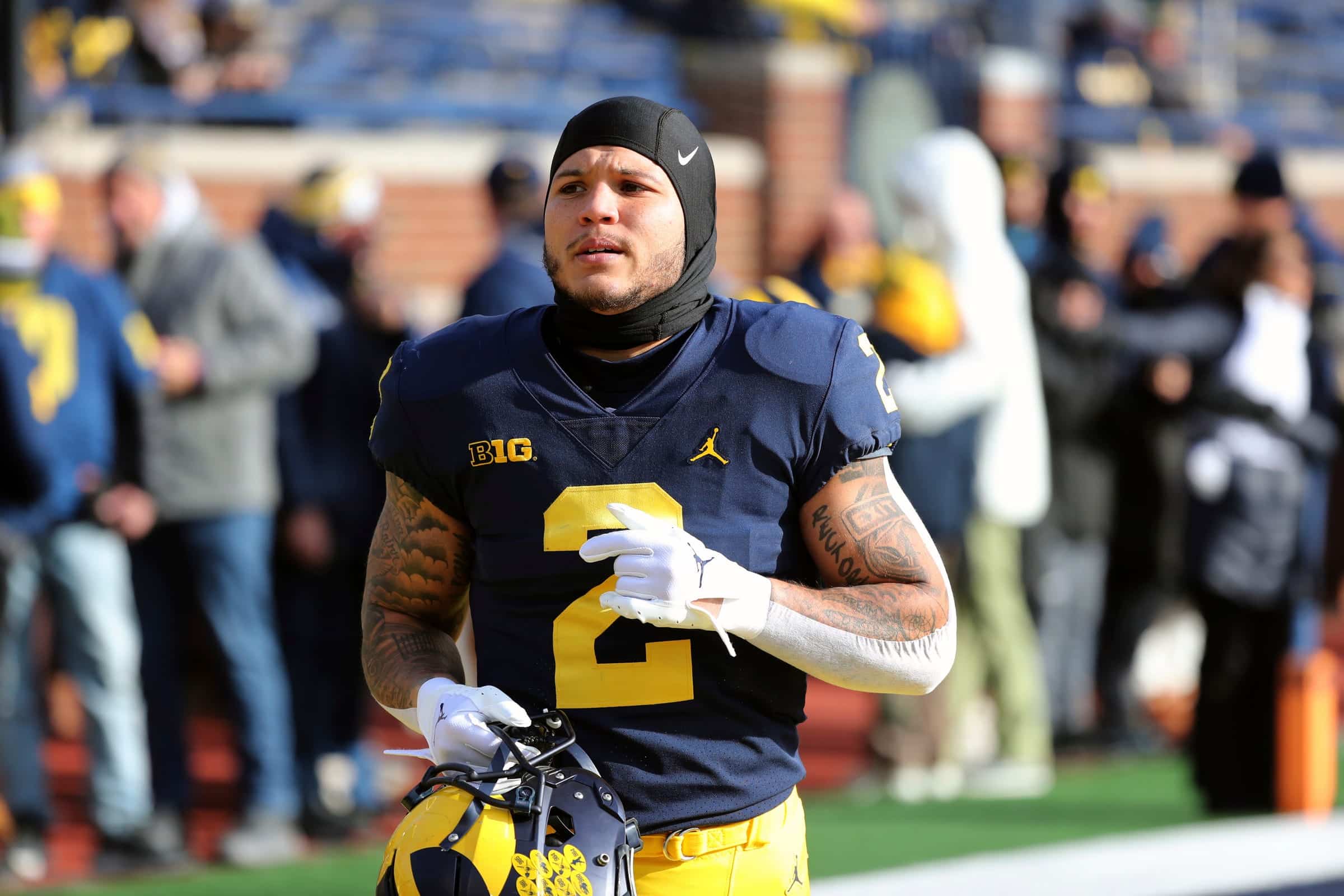 University of Michigan running back Blake Corum jogs off field while holding helmet