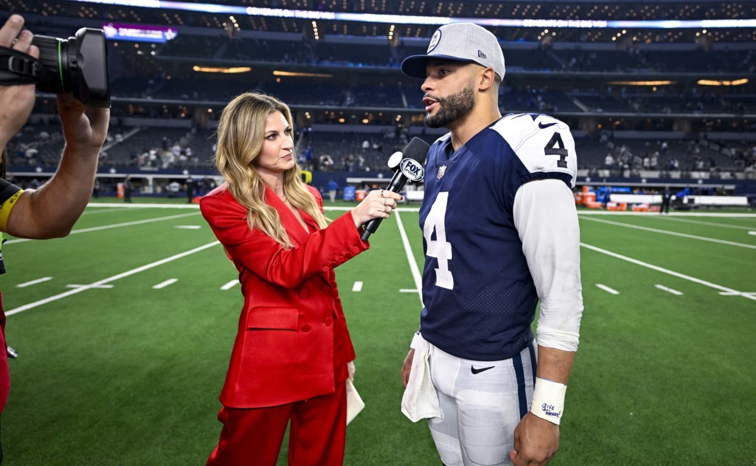 Fox sideline reporter Erin Andrews wearing bright red suit while interviewing Dallas Cowboys quarterback Dak Prescott after NFL game