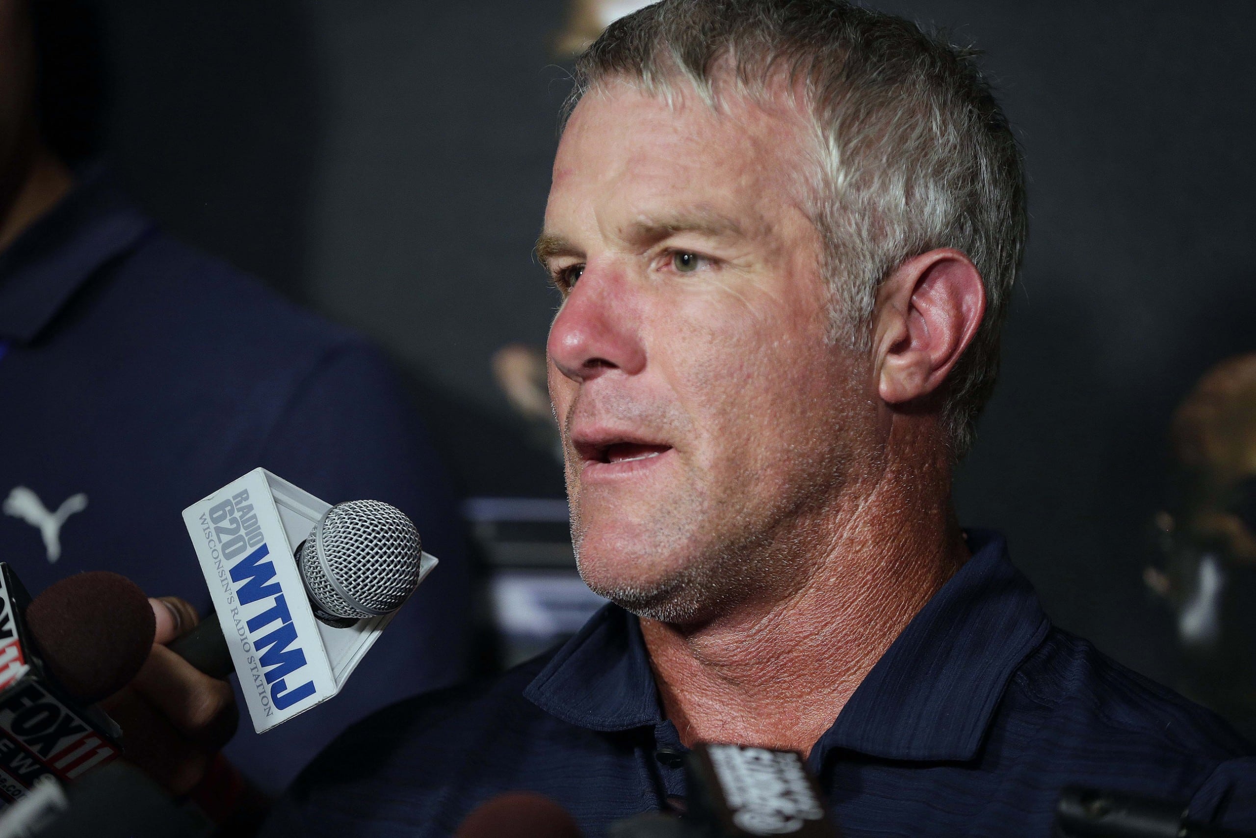 Former NFL quarterback Brett Favre answers media questions while sitting at podium