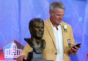 Brett Favre standing next to his bust during NFL Hall of Fame induction ceremony