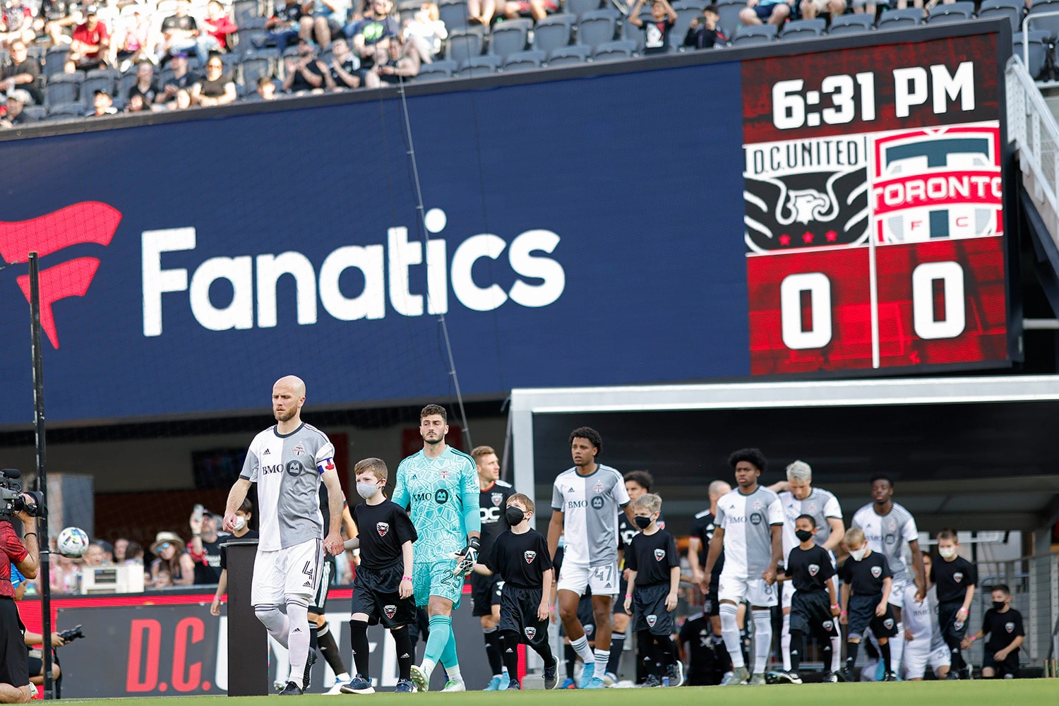 Toronto FC and DC United squads walk in front of Fanatics advertisement