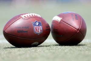 Two official NFL footballs on sideline of field