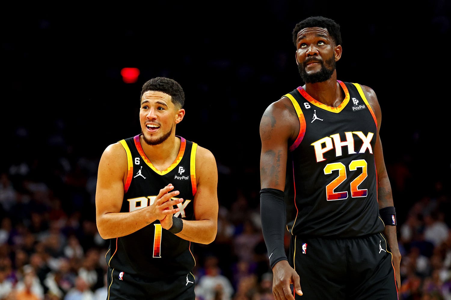Phoenix Suns players Devin Booker and Deandre Ayton standing on basketball court