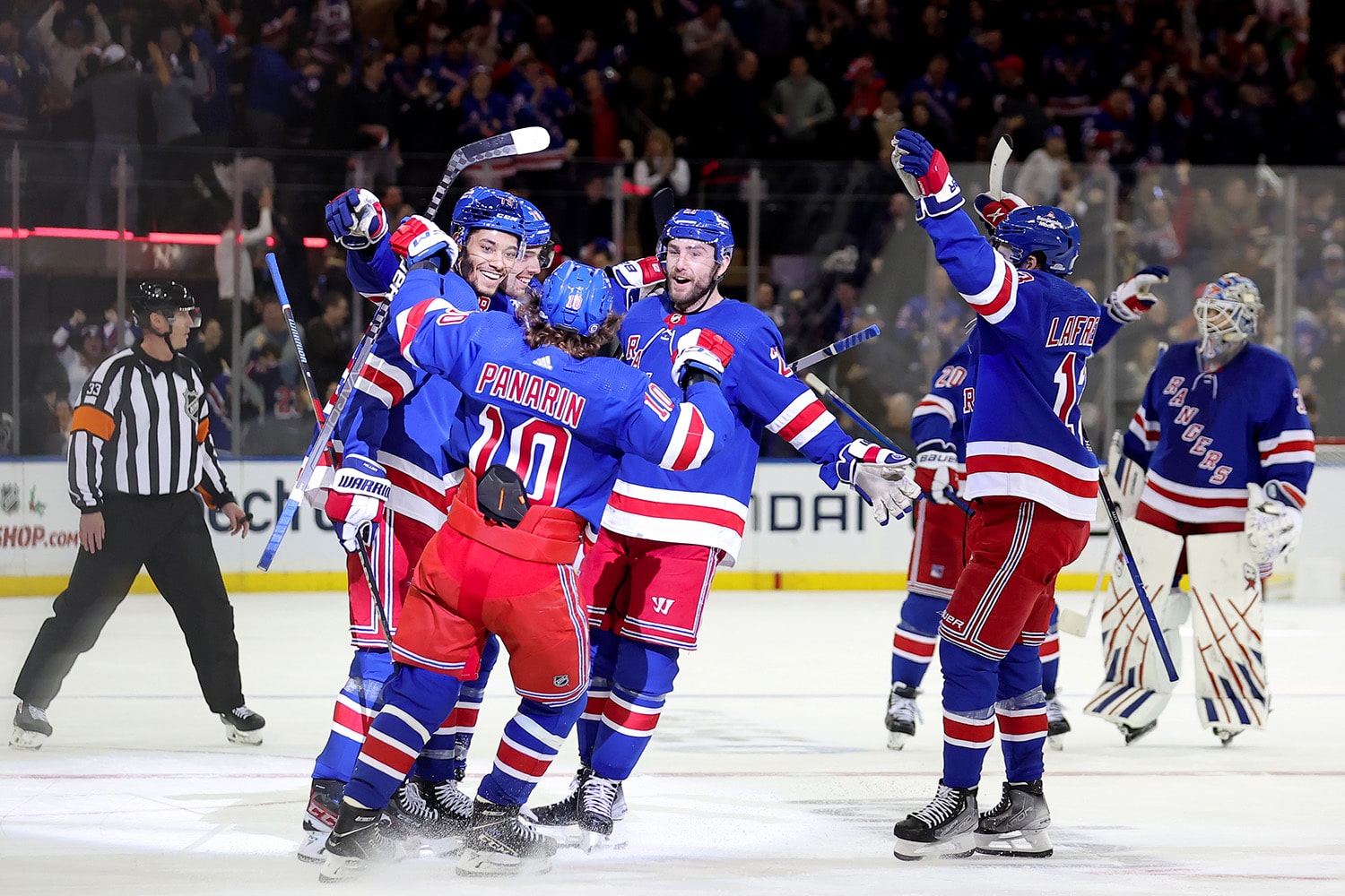 New York Rangers players celebrate together in the middle of the ice