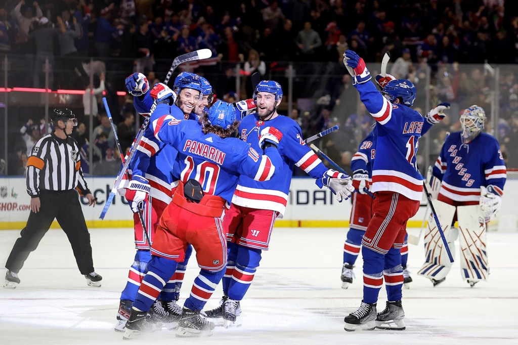 New York Rangers players celebrate together in the middle of the ice