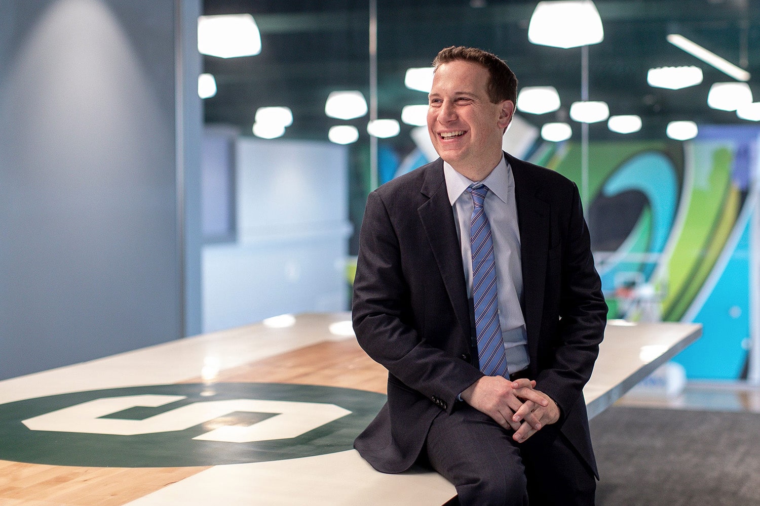 New Phoenix Suns owner Mat Ishbia smiles while leaning on table