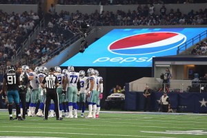 Dallas Cowboys team forms huddle in front of Pepsi advertisement