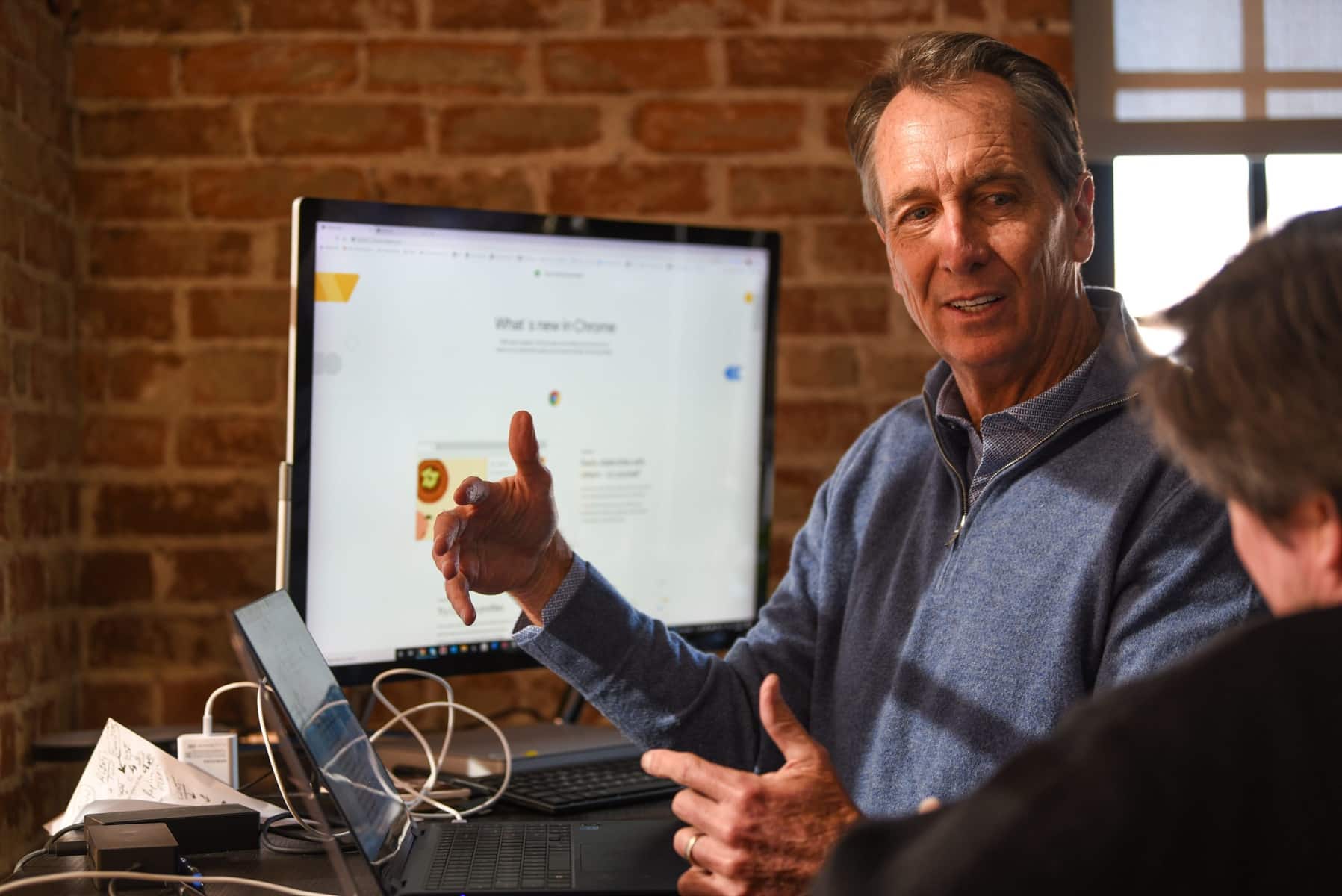 Football analyst and PFF investor Chris Collinsworth talks to man in front of computers