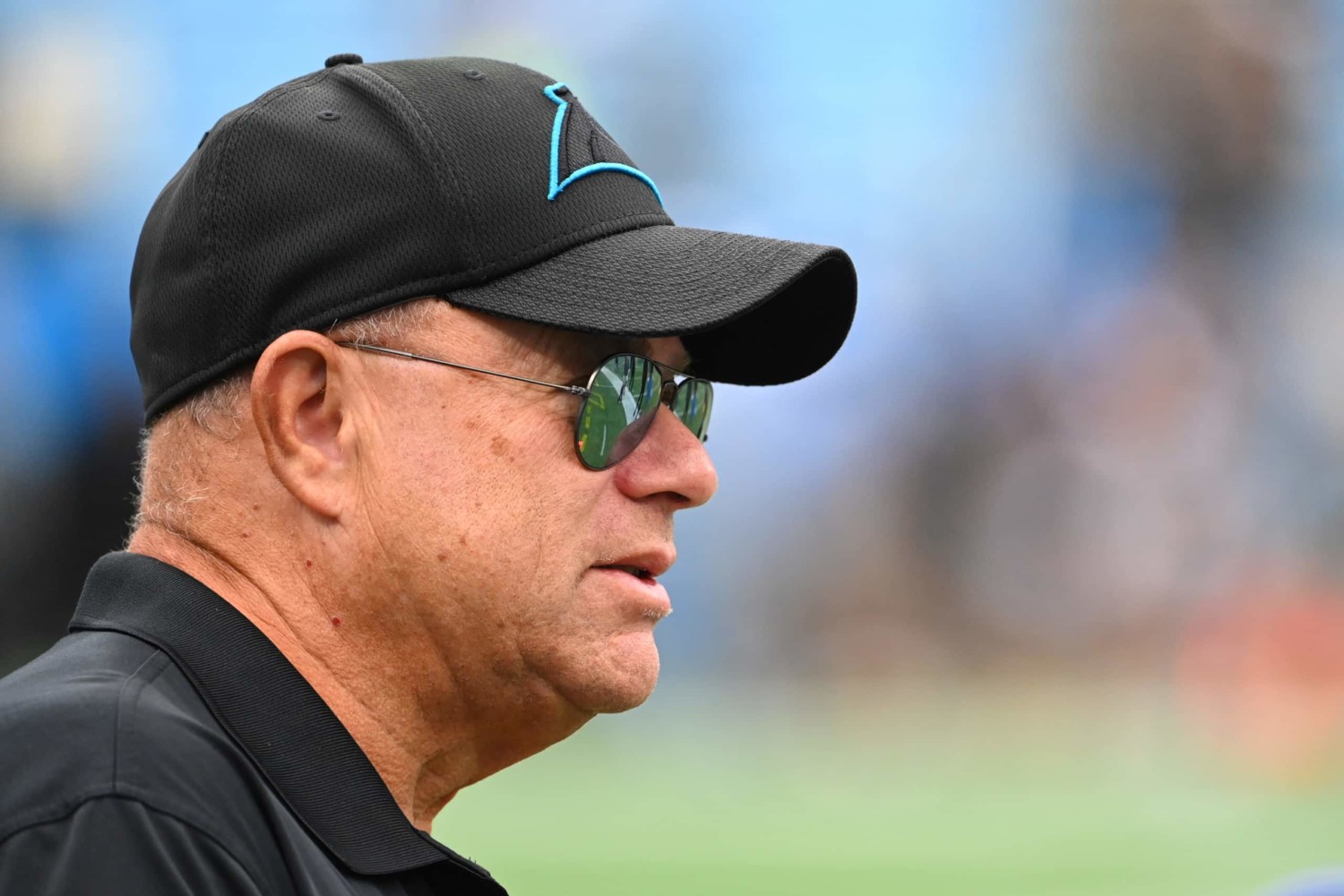 Carolina Panthers owner David Tepper watches from sideline while wearing sunglasses and hat
