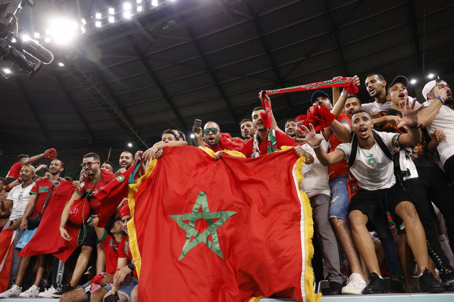 Moroccan fans hold up national flag and scarfs while supporting their team