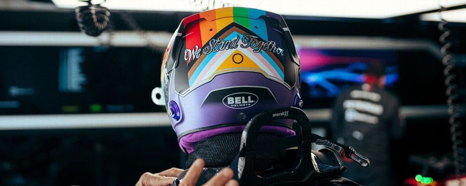 F1 driver Lewis Hamilton in helmet with "We Stand Together" sticker