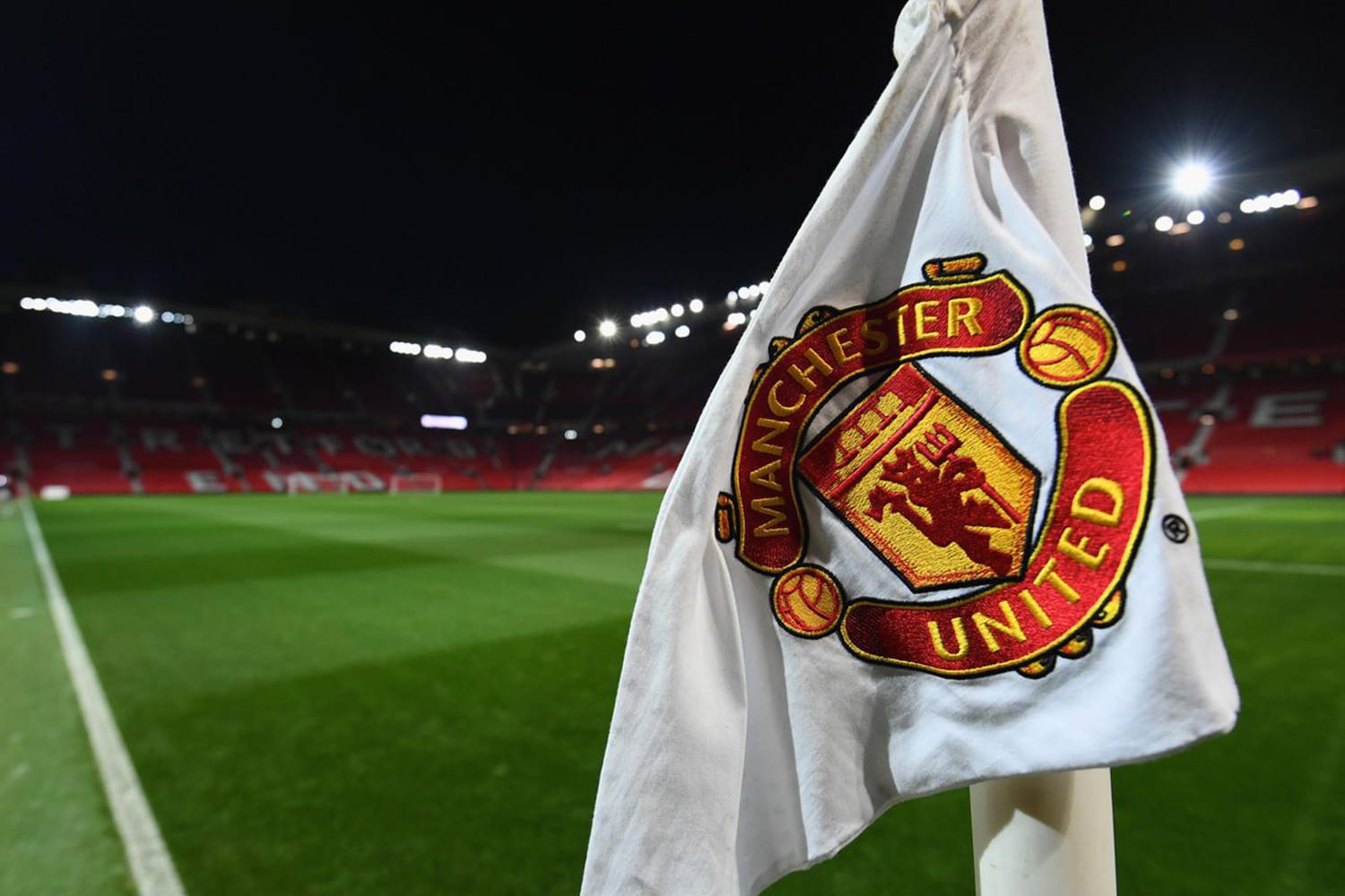 A view of a Manchester United corner flag during a night match.