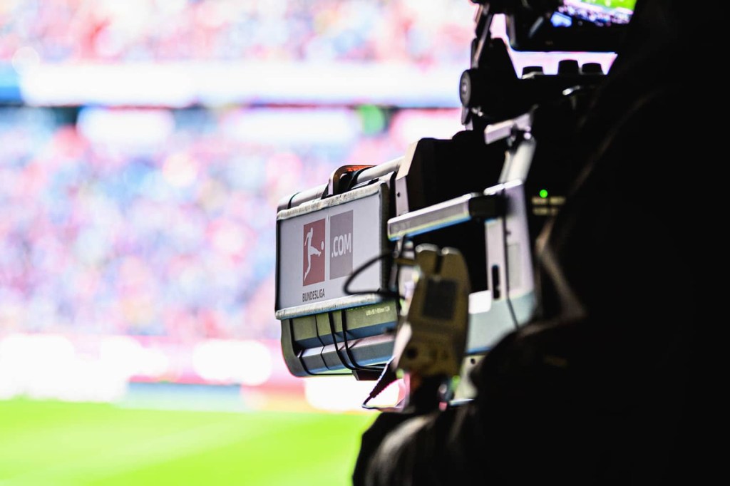 A Bundesliga broadcast camera is aimed towards the field.