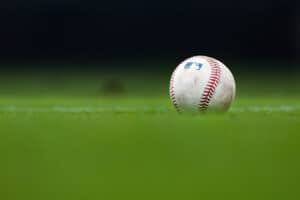 A detailed view of an MLB baseball sitting on grass.