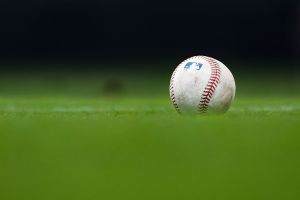 A detailed view of an MLB baseball sitting on grass.