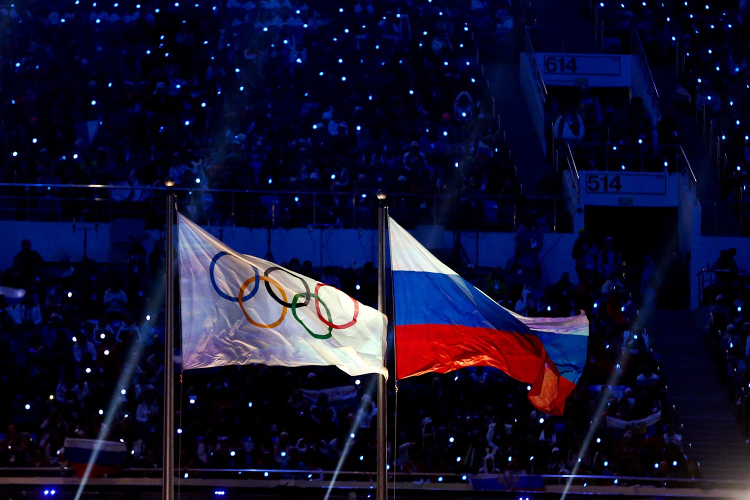 The flag of the IOC flies next to the flag of the Russian Federation at night during the closing ceremony for Sochi 2014.