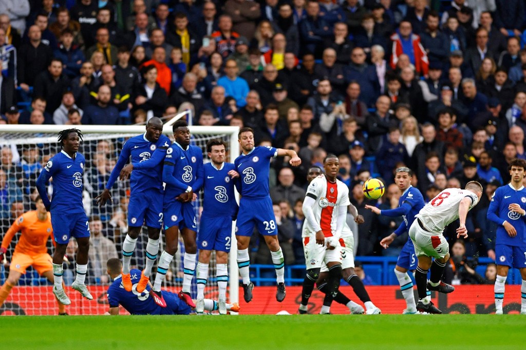 Chelsea FC players attempt to block a free kick from James Ward-Prowse during a Premier League match.