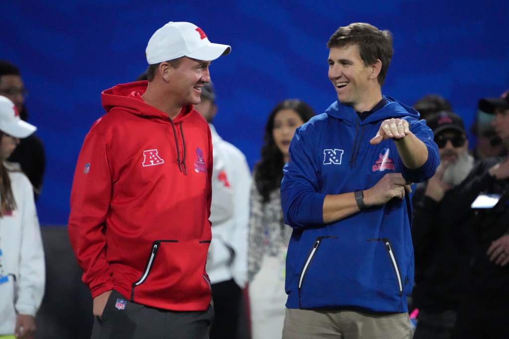 Peyton and Eli Manning standing together and smiling at the Pro Bowl Games.