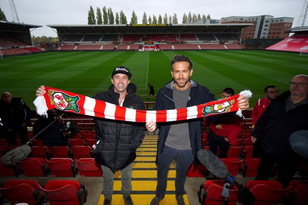 Rob McElhenney and Ryan Reynolds holding up a Wrexham AFC scarf.