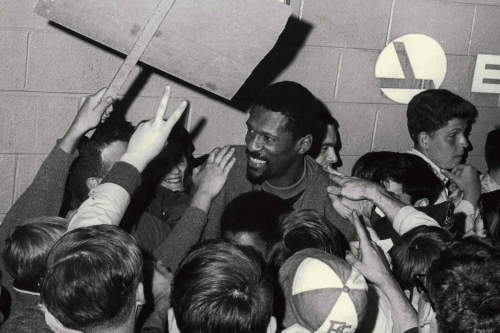 An archive photo of Bill Russell surrounded by fans.