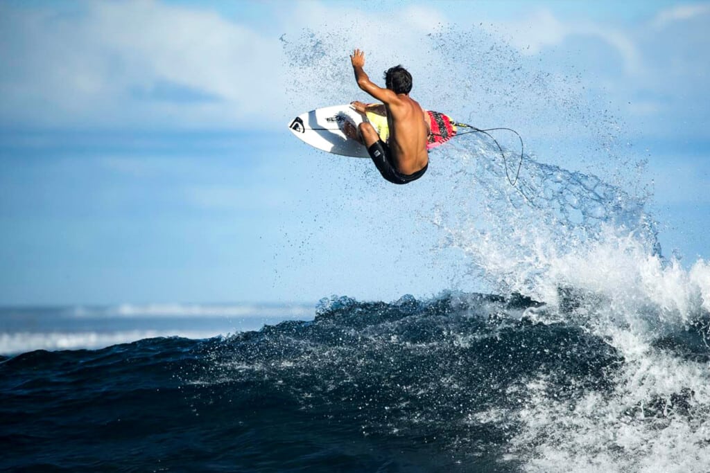 A surfer rides a Quicksilver board.
