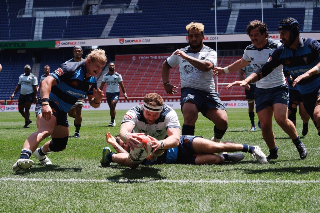A Major League Rugby player dives to score a try during a match.