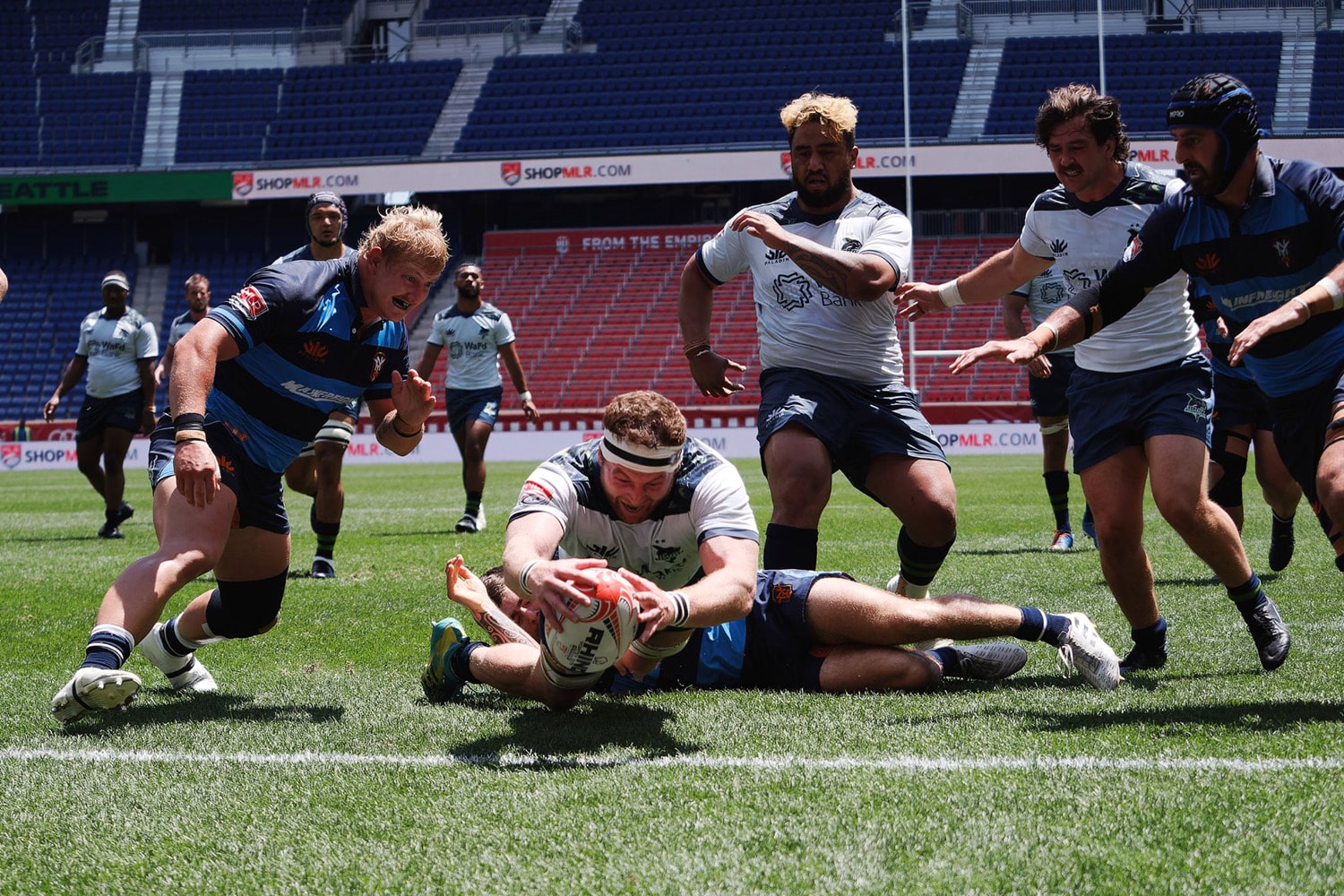 A Major League Rugby player dives to score a try during a match.