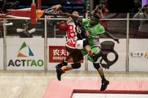 A SlamBall player dunks over another after jumping from a trampoline.