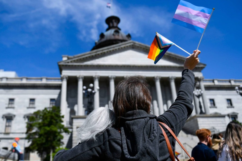 LGBTQ+ supporters raise flags representing the LGBTQ+ and transgender communities outside of the S.C. Statehouse on Wednesday, March 29, 2023.