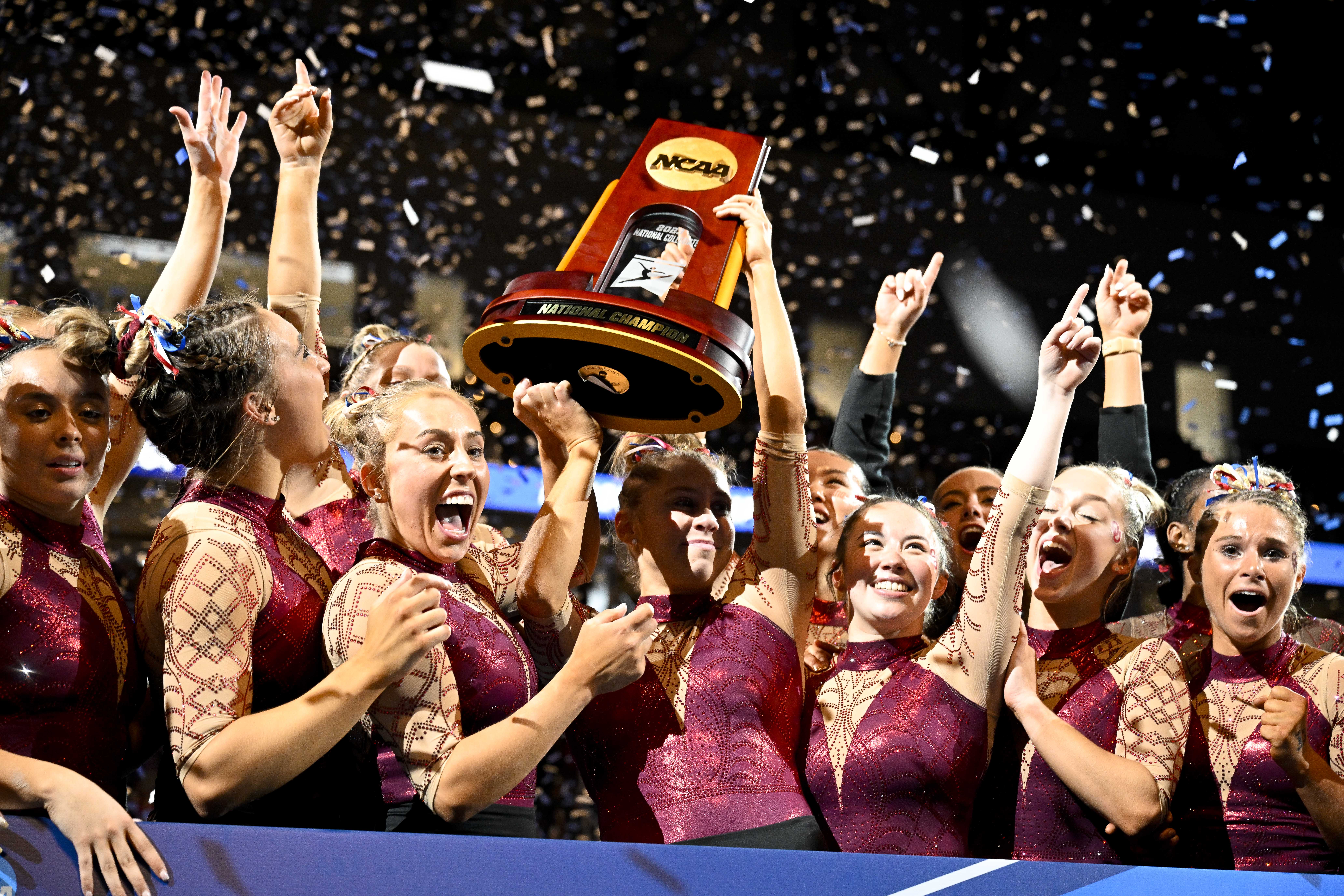 Apr 15, 2023; Fort Worth, TX, USA; The University of Oklahoma Sooners celebrate with the trophy as confetti falls after the Sooners win the national championship at the NCAA Women's National Gymnastics Tournament Championship at Dickies Arena.