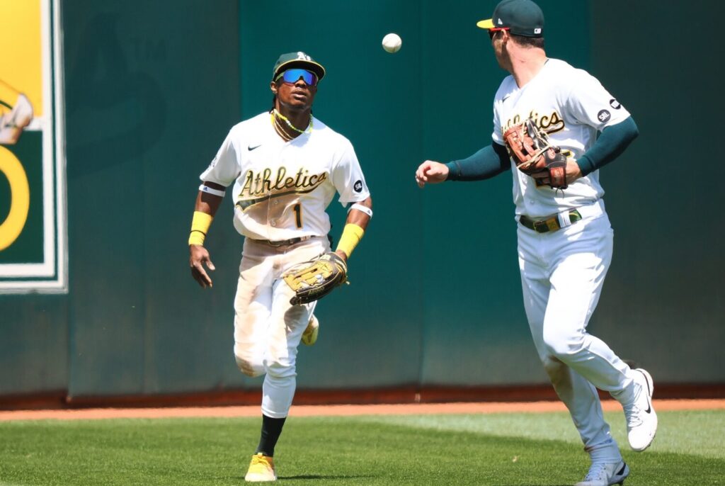 Oakland Athletics center fielder Esteury Ruiz (1) tosses the ball to left fielder Brett Rooker (25) after making an out against the Atlanta Braves during the ninth inning at Oakland-Alameda County Coliseum.