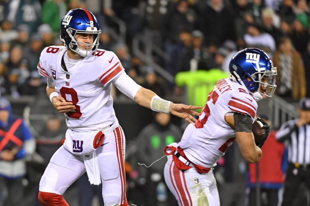 New York Giants quarterback Daniel Jones (8) hands the ball to running back Saquon Barkley (26) against the Philadelphia Eagles during an NFC divisional round game at Lincoln Financial Field.