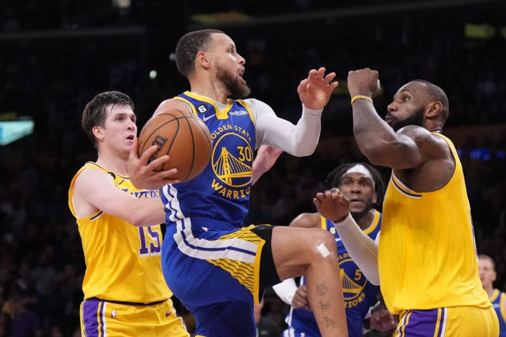 Golden State Warriors guard Stephen Curry shoots the ball against Los Angeles Lakers guard Austin Reaves and forward LeBron James in the second half of game four of the 2023 NBA playoffs at Crypto.com Arena.