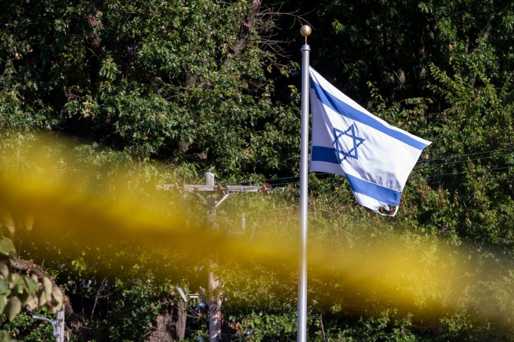 The flag of Israel waves in the wind above crime scene tape outside Margolin Hebrew Academy after a man armed with a handgun first tried to enter the school and then began firing his gun outside the school before fleeing in Memphis, Tenn., on Monday, July 31, 2023.