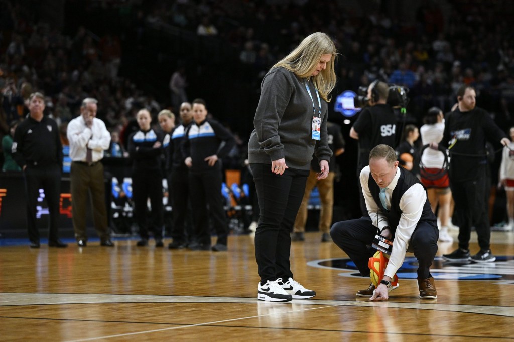 Mar 31, 2024; Portland, OR, USA; NCAA officials measure the three point line while coaches from the Texas Longhorns and NC State Wolfpack watch with referees in the finals of the Portland Regional of the NCAA Tournament at the Moda Center center.