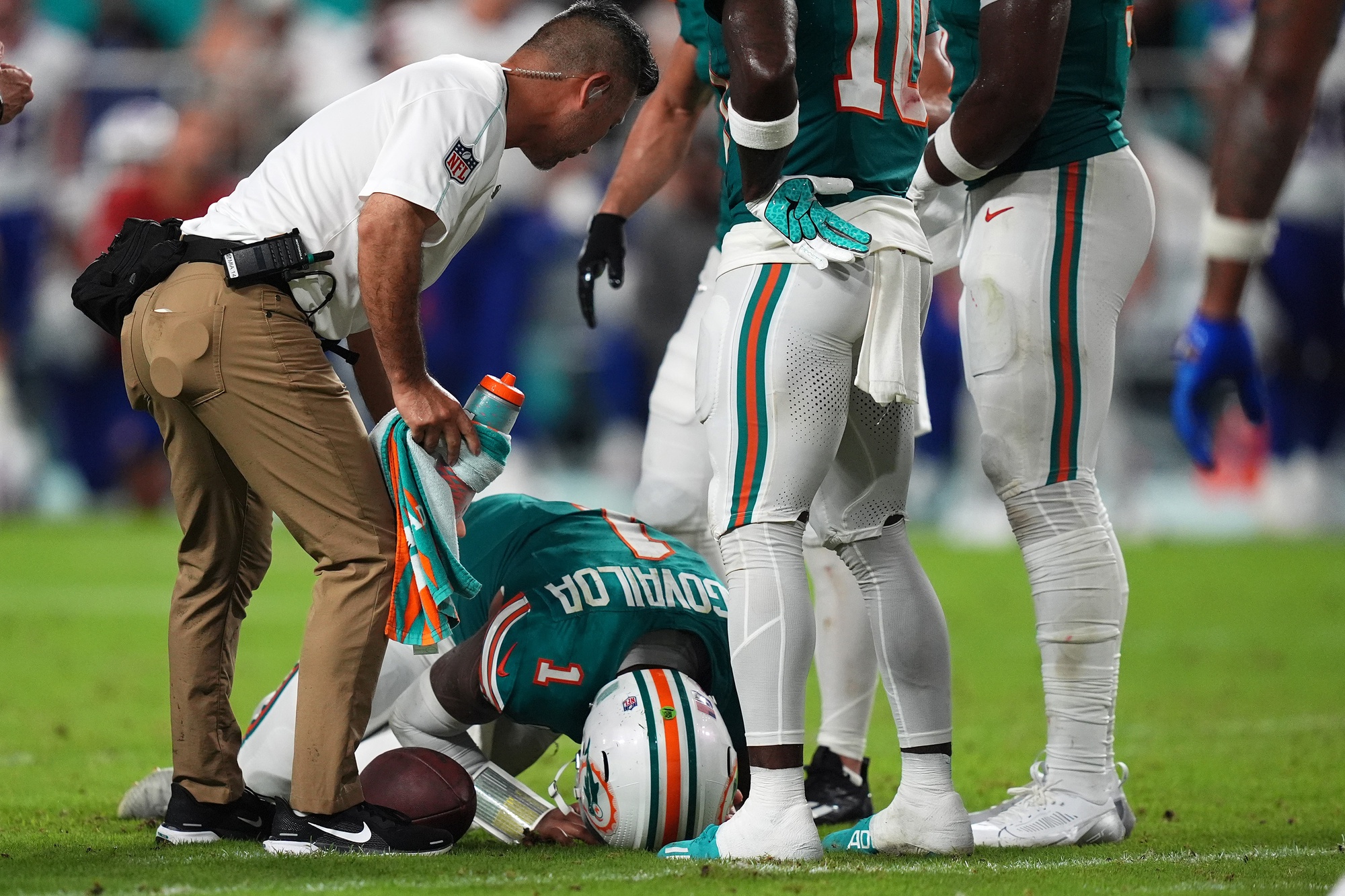 A member of the Miami Dolphins training staff attends to quarterback Tua Tagovailoa