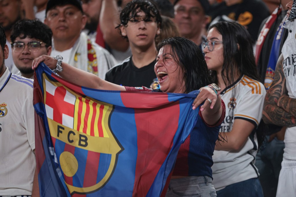 Aug 3, 2024; East Rutherford, NJ, USA; A Barcelona fan celebrates in front of against Real Madrid fans during the second half of an international friendly at MetLife Stadium. 