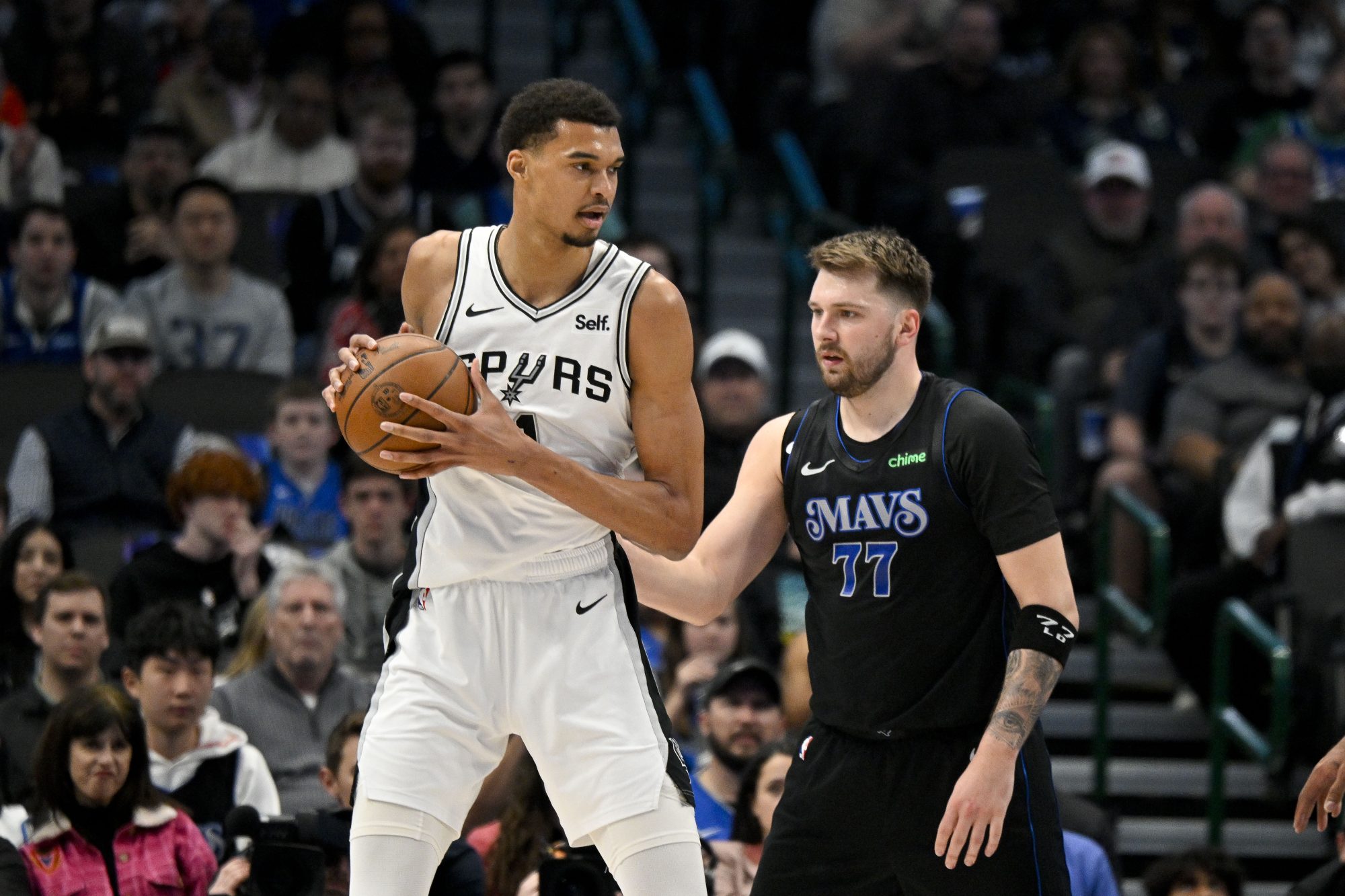 Feb 14, 2024; Dallas, Texas, USA; San Antonio Spurs center Victor Wembanyama (1) looks to move the ball past Dallas Mavericks guard Luka Doncic (77) during the fist quarter at the American Airlines Center.