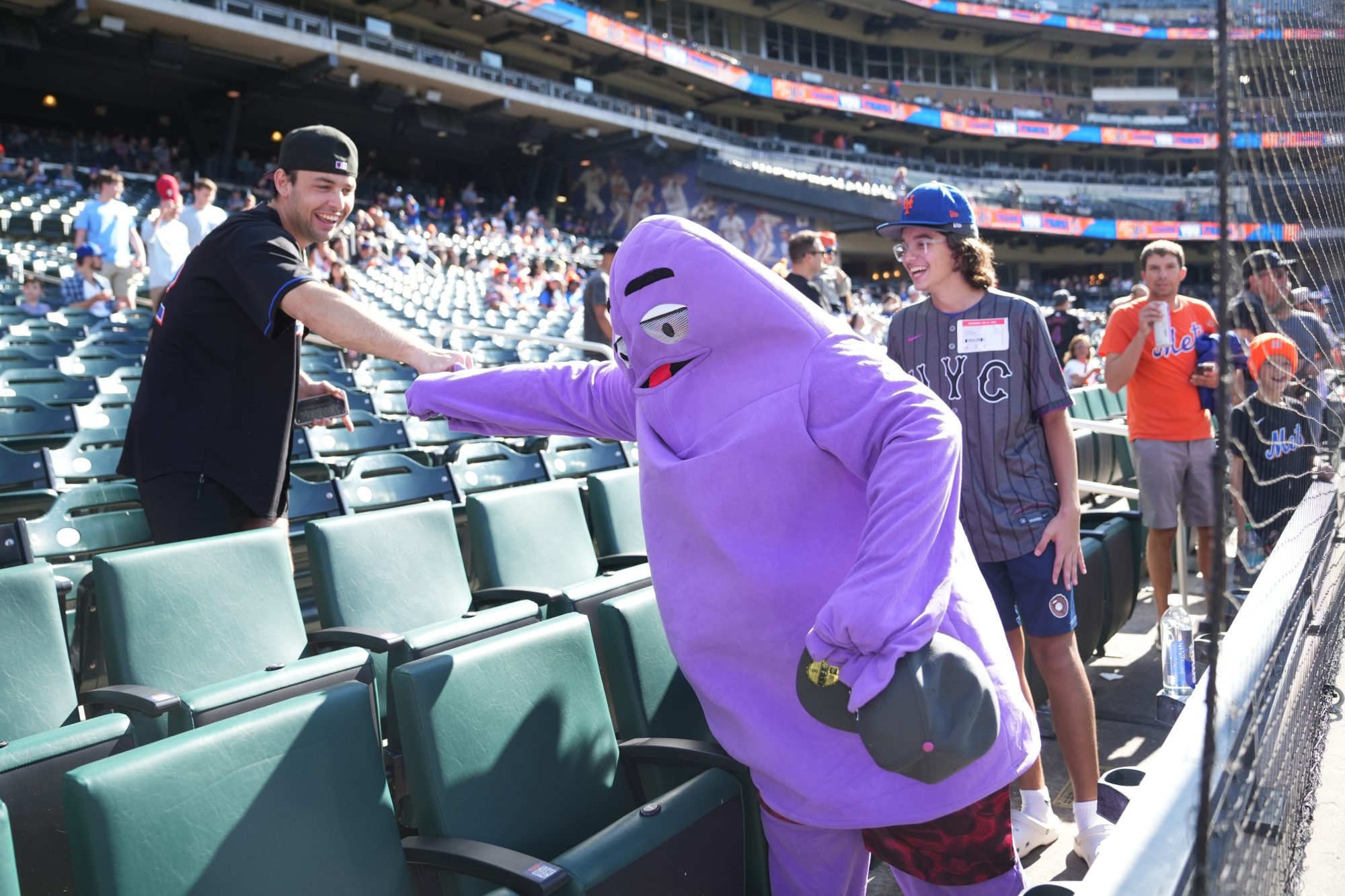 Sep 21, 2024; New York City, New York, USA; A New York Mets fan in a Grimace costume gives knuckles before the game against the Philadelphia Phillies at Citi Field.