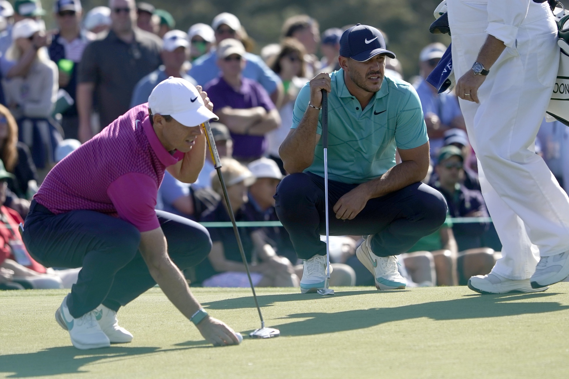 Apr 7, 2022; Augusta, Georgia, USA; Rory McIlroy (left) and Brooks Koepka set up to putt on no. 9 during the first round of The Masters golf tournament.