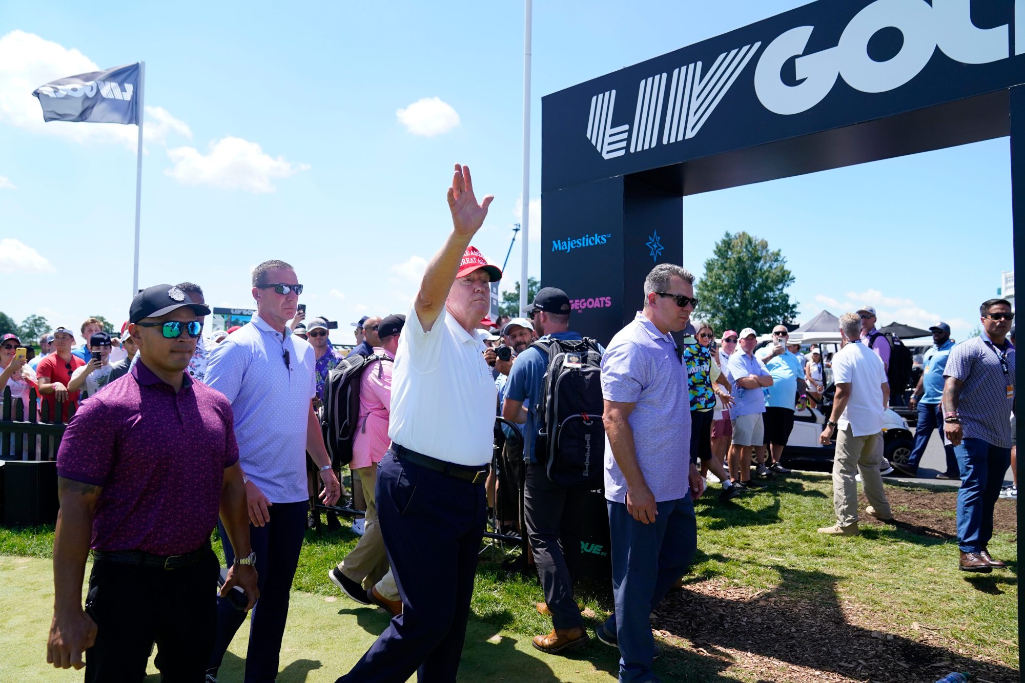 Former President Donald Trump waves to the crowd as he exits the putting green with his aide Walt Nauta, left, during the final round of the LIV Golf Bedminster golf tournament at Trump National Bedminster on Sunday, Aug. 13, 2023.