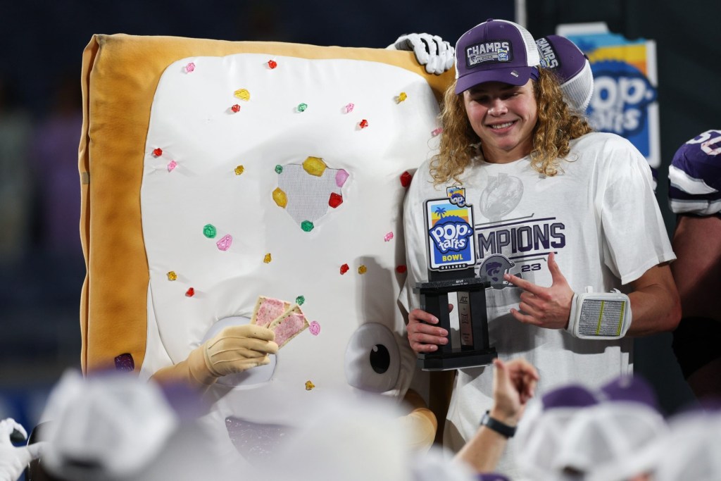 Dec 28, 2023; Orlando, FL, USA;  Kansas State Wildcats quarterback Avery Johnson (2) is given the MVP trophy after beating the North Carolina State Wolfpack in the Pop-Tarts bowl at Camping World Stadium. 