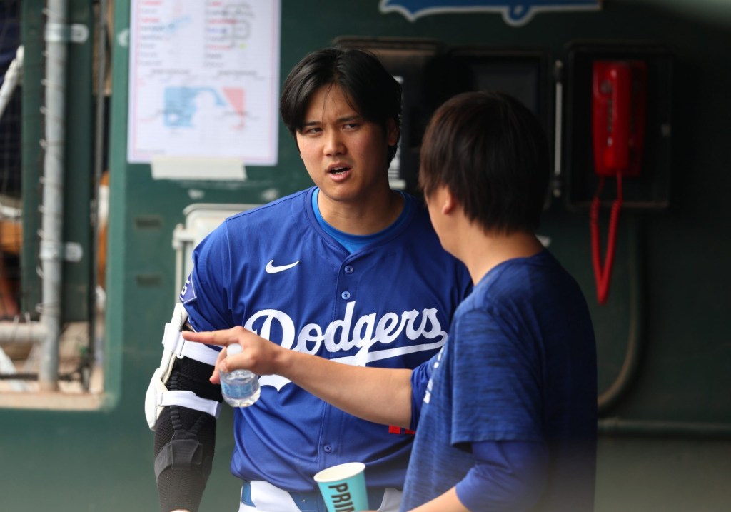 Mar 12, 2024; Phoenix, Arizona, USA; Los Angeles Dodgers designated hitter Shohei Ohtani talks with translator Ippei Mizuhara in the dugout against the San Francisco Giants during a spring training baseball game at Camelback Ranch-Glendale.