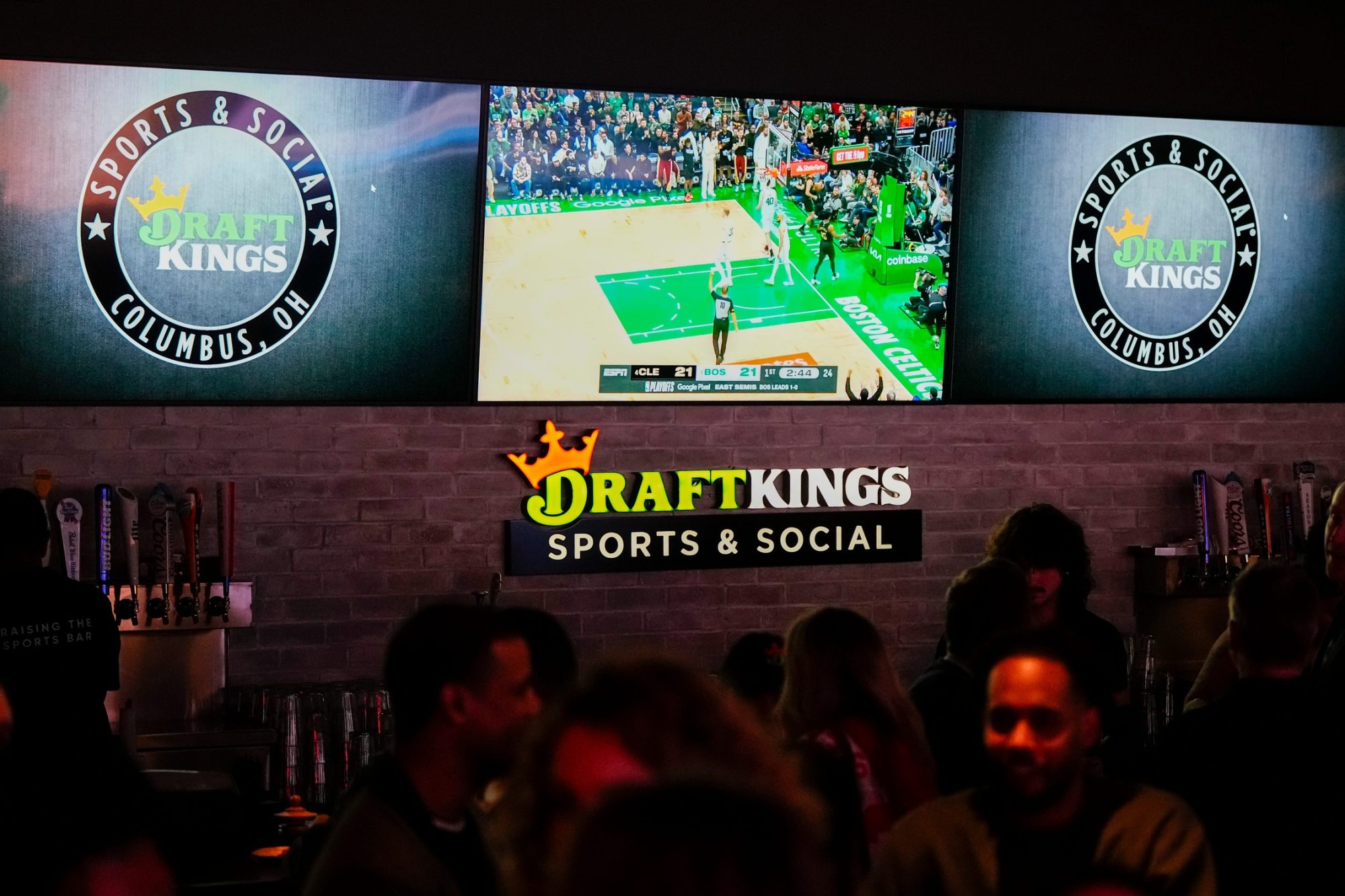 May 9, 2024; Columbus, OH, USA; Sports are shown on TVs behind the bar as guests enjoy the grand opening of DraftKings Sports & Social in the Short North. Though there are no on-site betting windows, eligible customers can place bets through the DraftKings app.